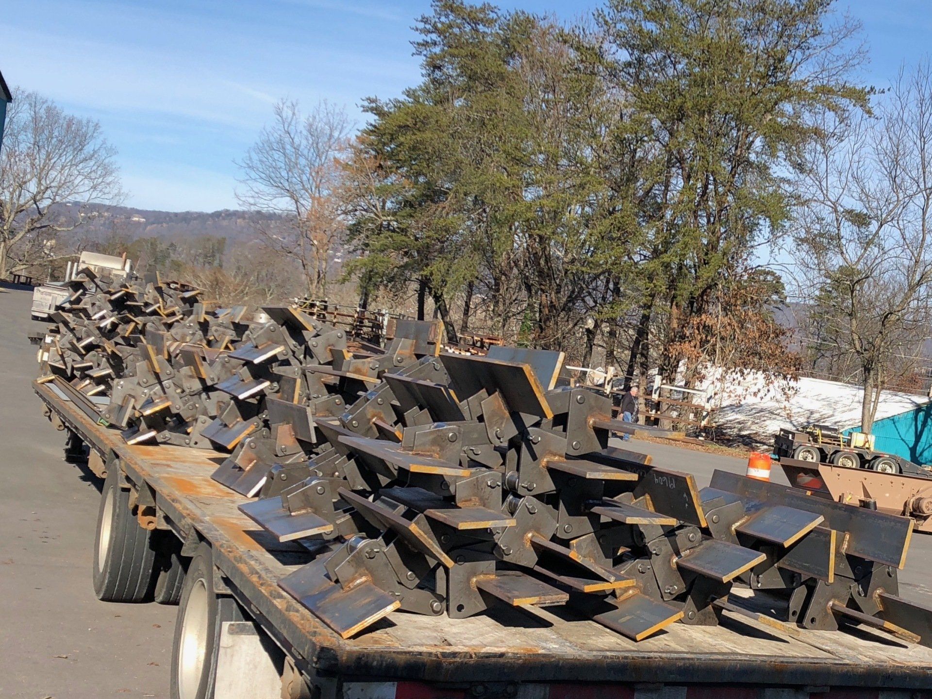 A trailer filled with a lot of metal pieces on a road.