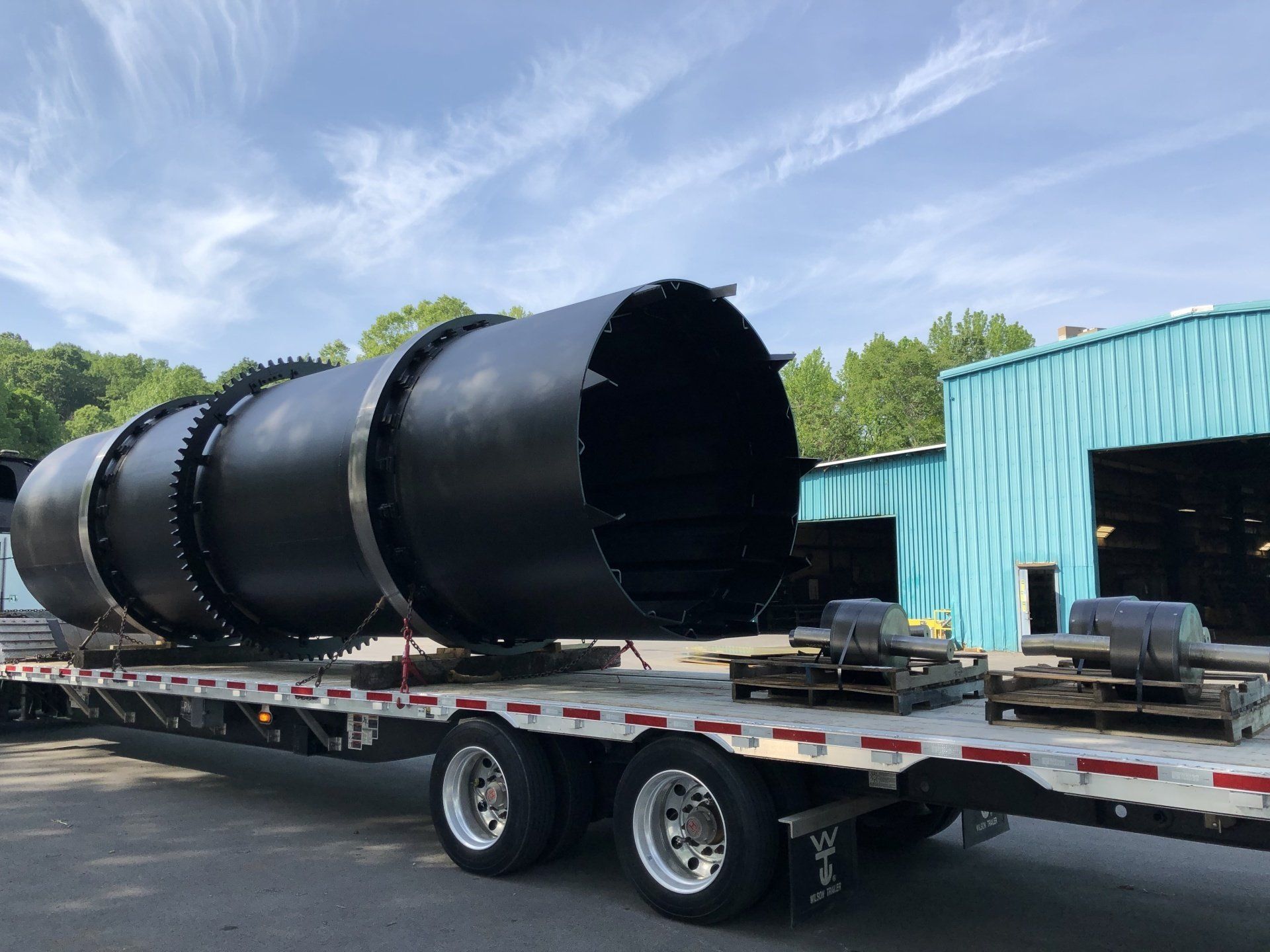 A large black pipe is sitting on top of a semi trailer.