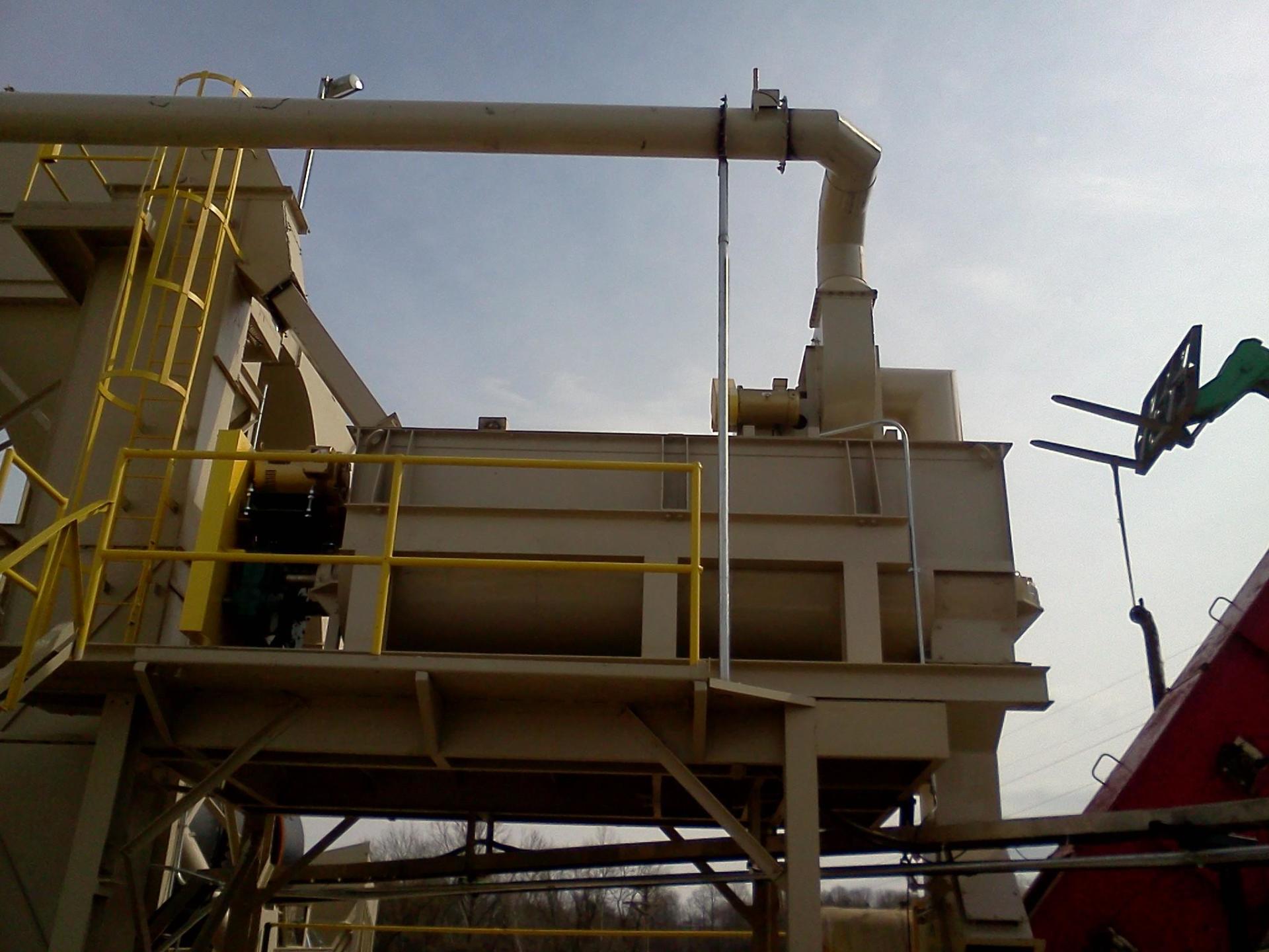 A large machine with a yellow railing is being lifted by a crane