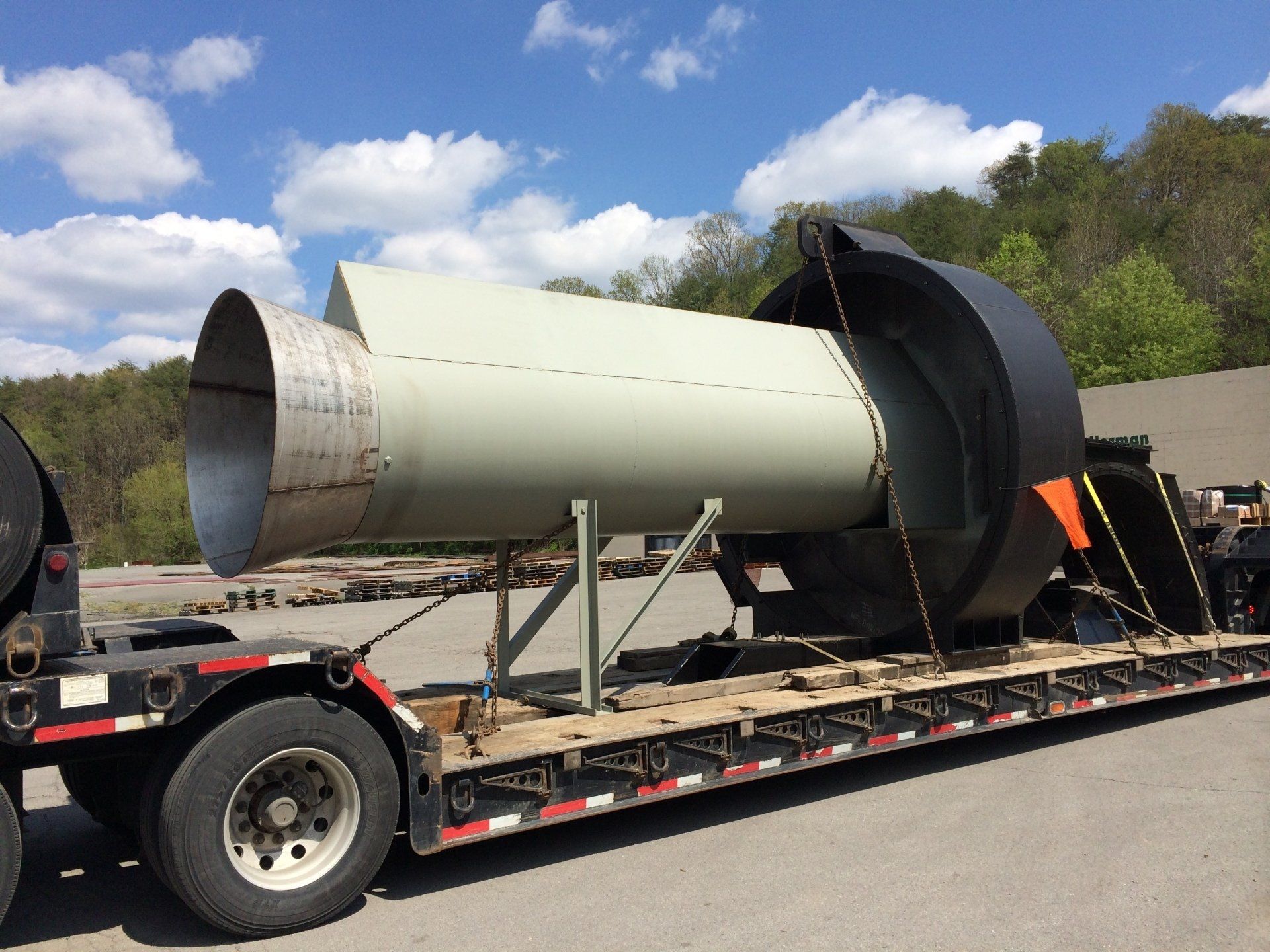 A large pipe is being transported on a trailer