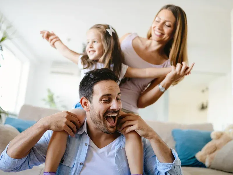 A man is carrying a little girl on his shoulders.
