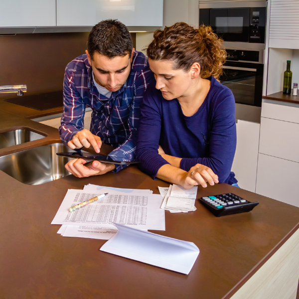 An image showing an insured couple reviewing financial documents at a table, representing permanent life insurance policies.