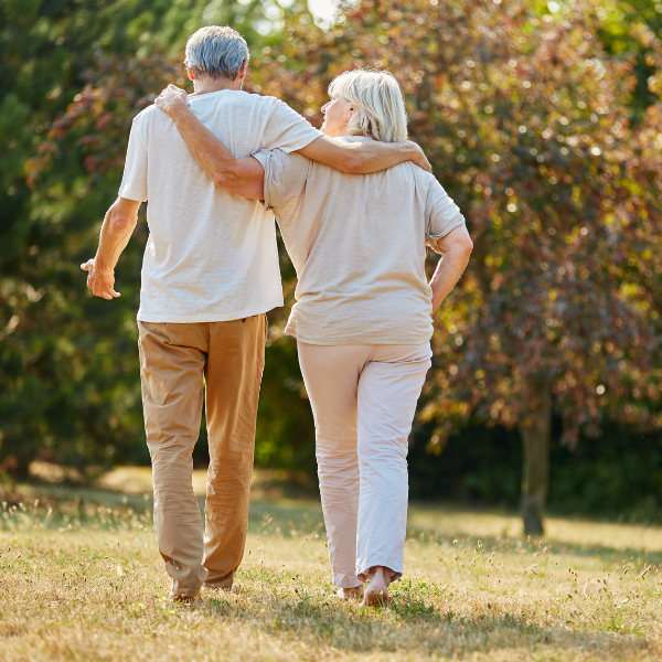 An image showing an elderly couple holding hands and walking in a garden represents whole-life insurance benefits.
