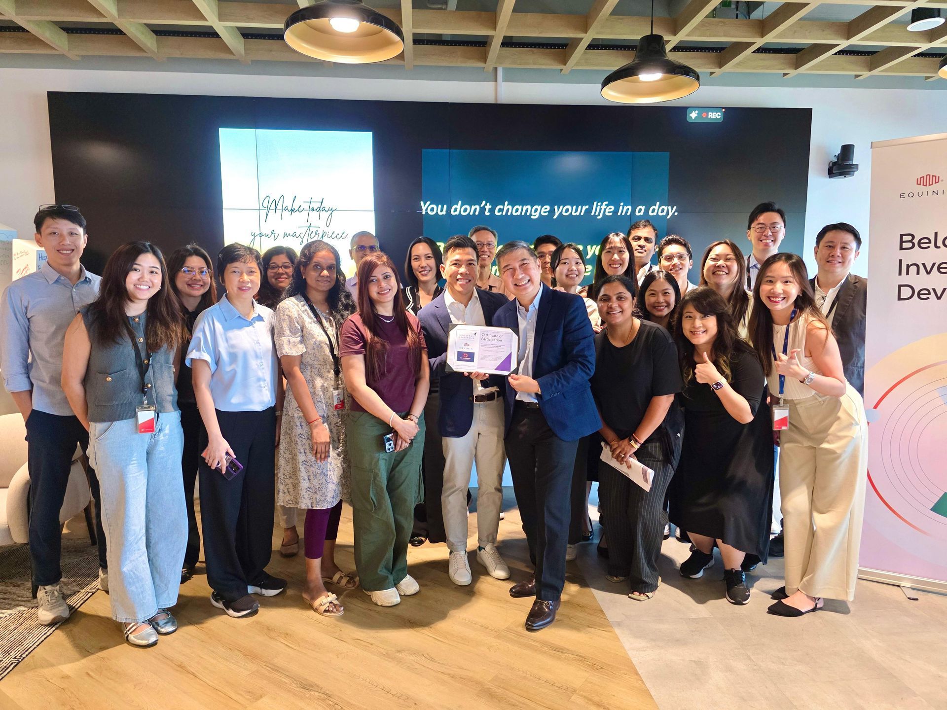 Group of people posing with an award in a modern office, smiling.