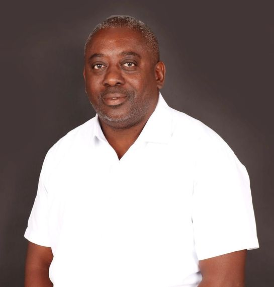 Man in white shirt against a dark background, looking forward.