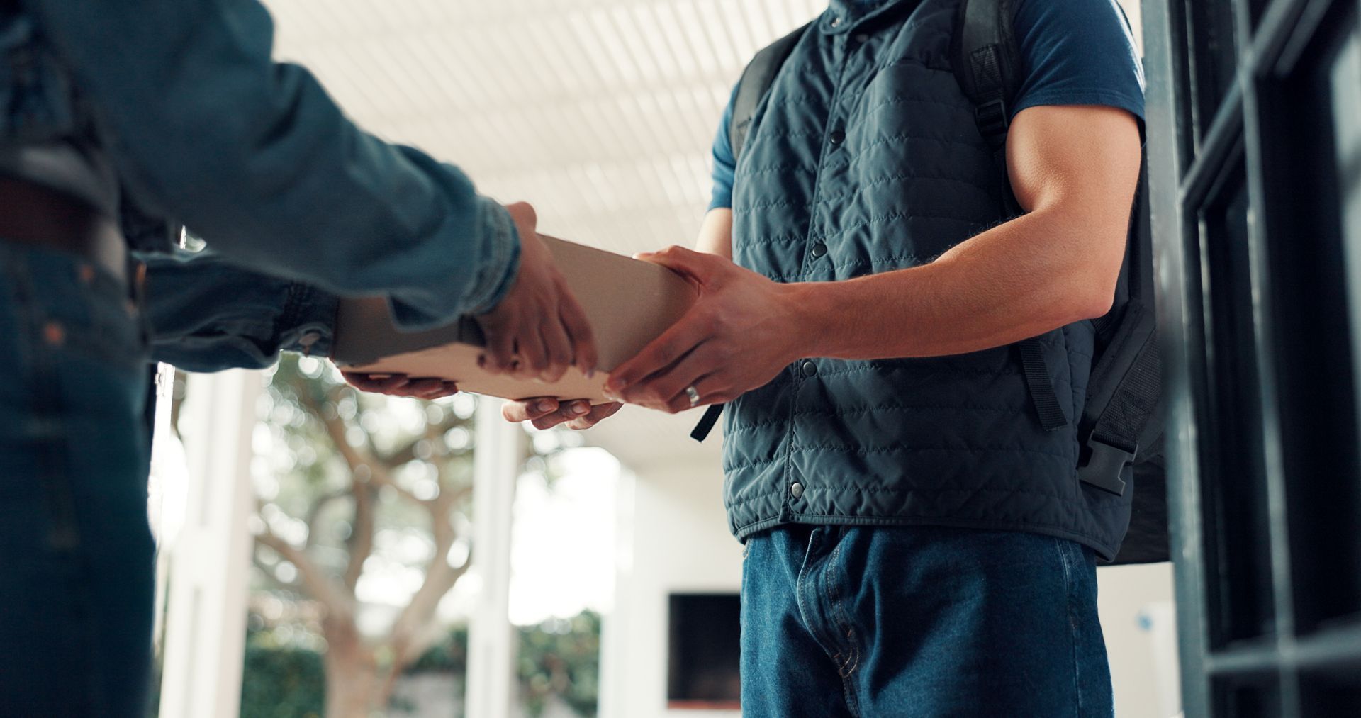 Person receiving a cardboard box from a delivery person on a porch.