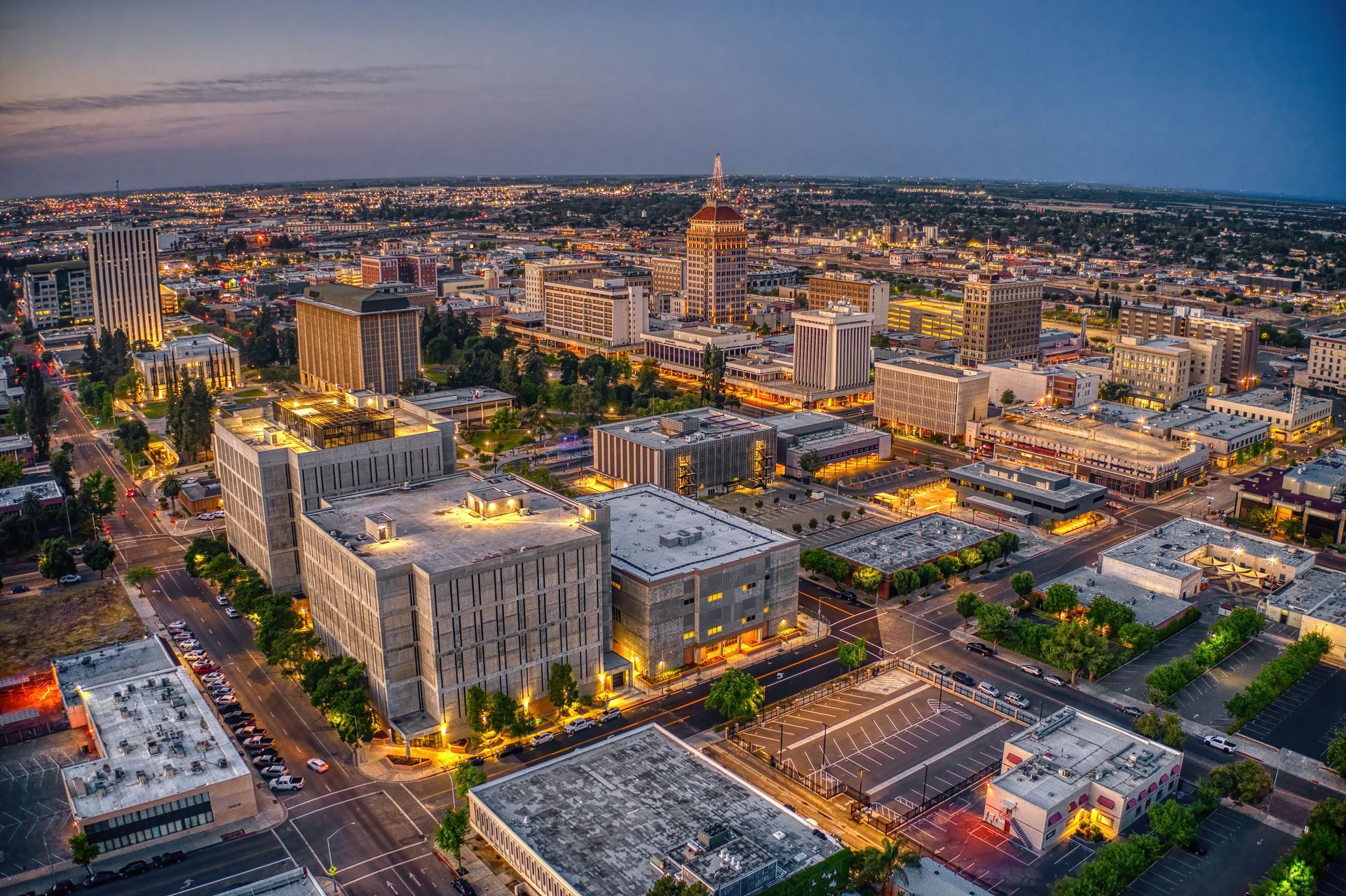 Aerial view of downtown Boise, Idaho at dusk, showcasing city lights, buildings, and capitol dome.