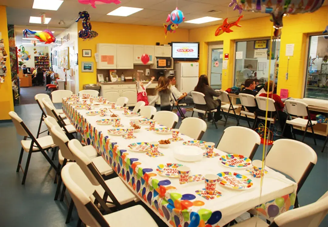A room with tables and chairs set up for a birthday party