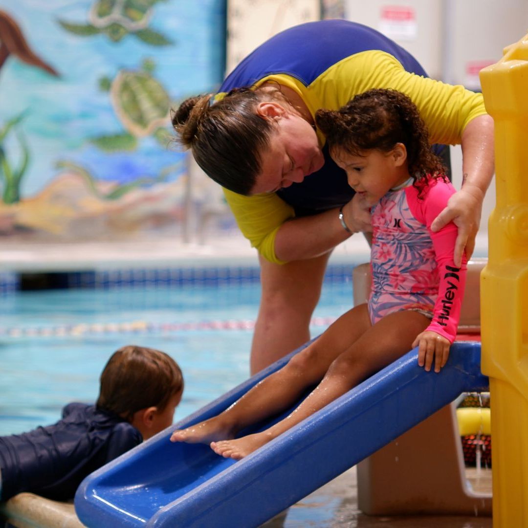 A woman helps a little girl on a hurley slide