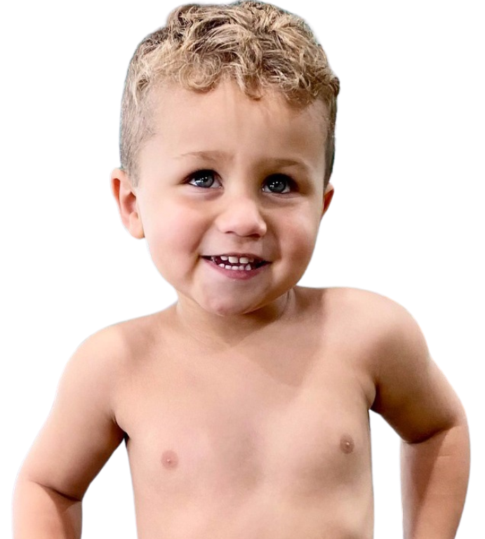 A young boy without a shirt is smiling for the camera