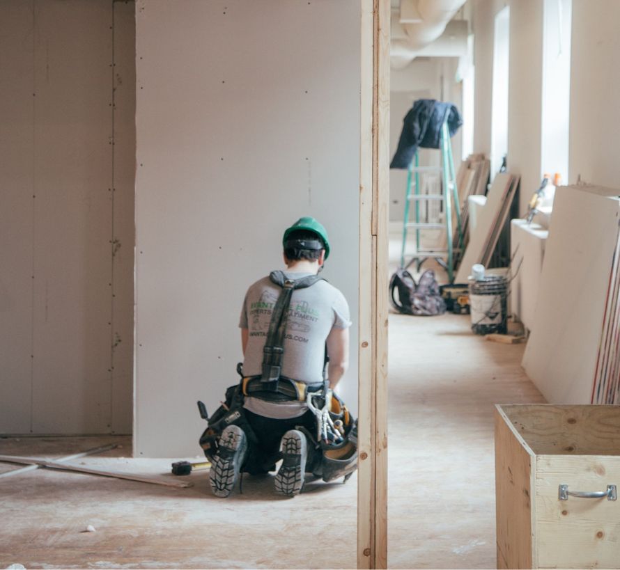 A man is sitting on the floor in a room under construction.