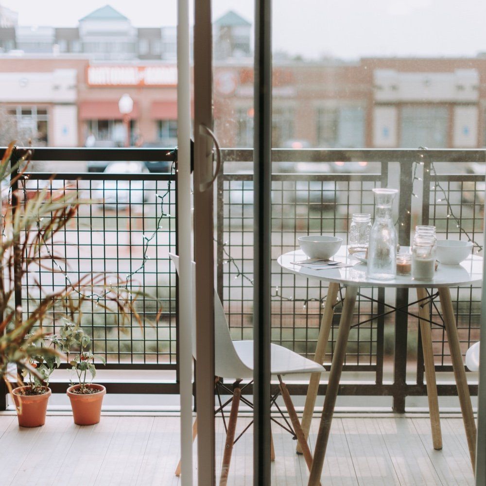 A balcony with a table and chairs and potted plants