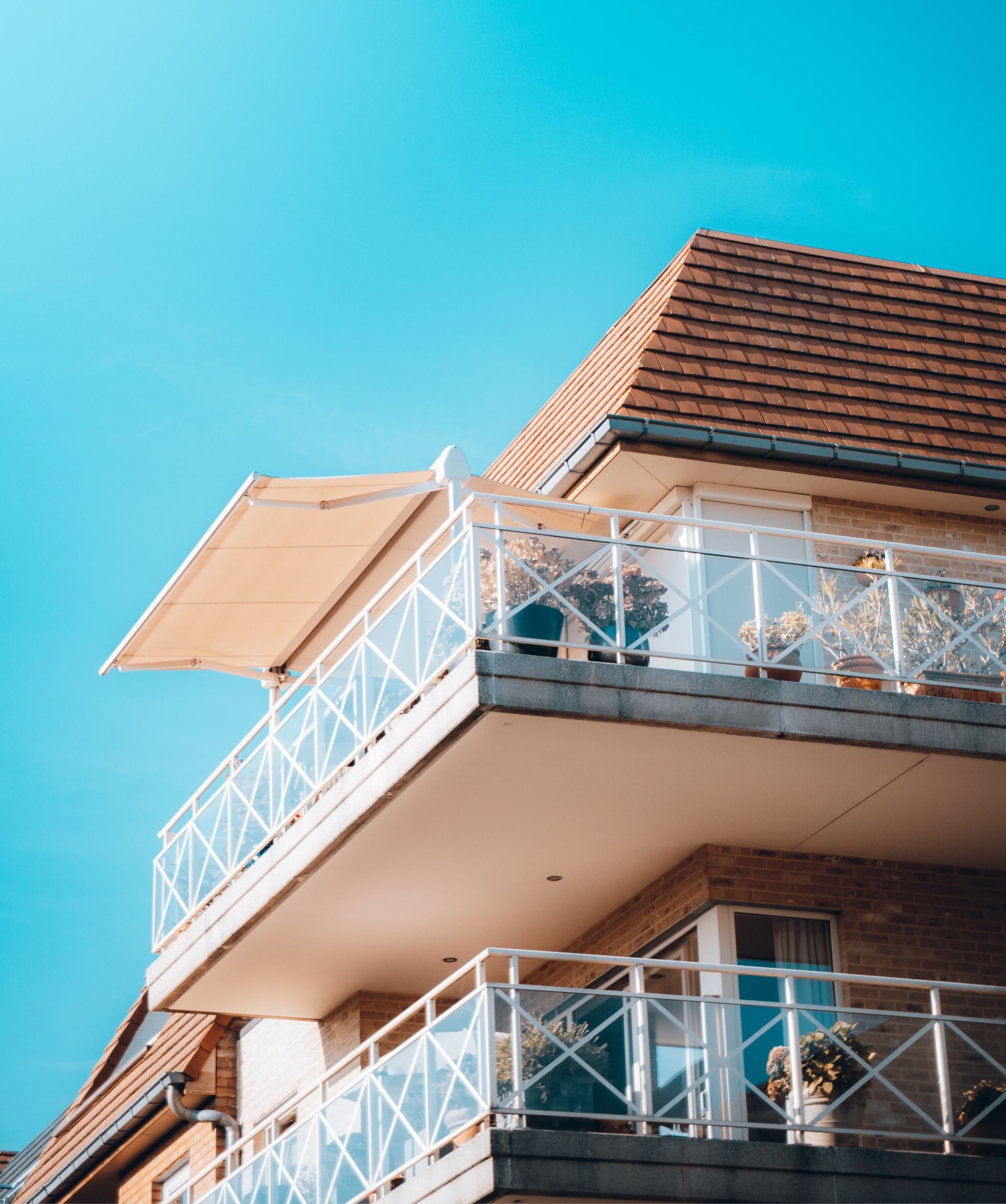 A house with a balcony and a blue sky in the background.