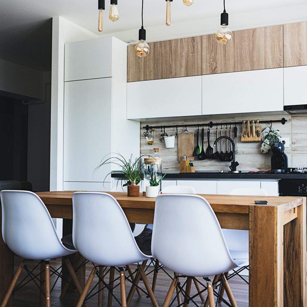 A kitchen with a wooden table and white chairs