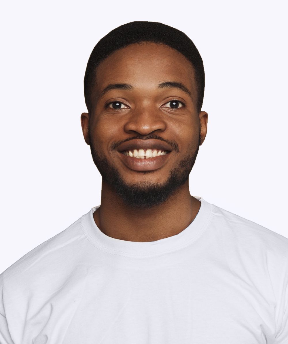 A man with a beard is wearing a white shirt and smiling.