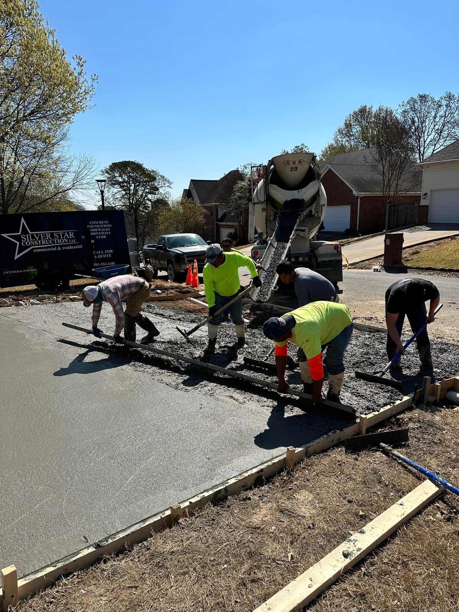 A group of construction workers are working on a concrete driveway.