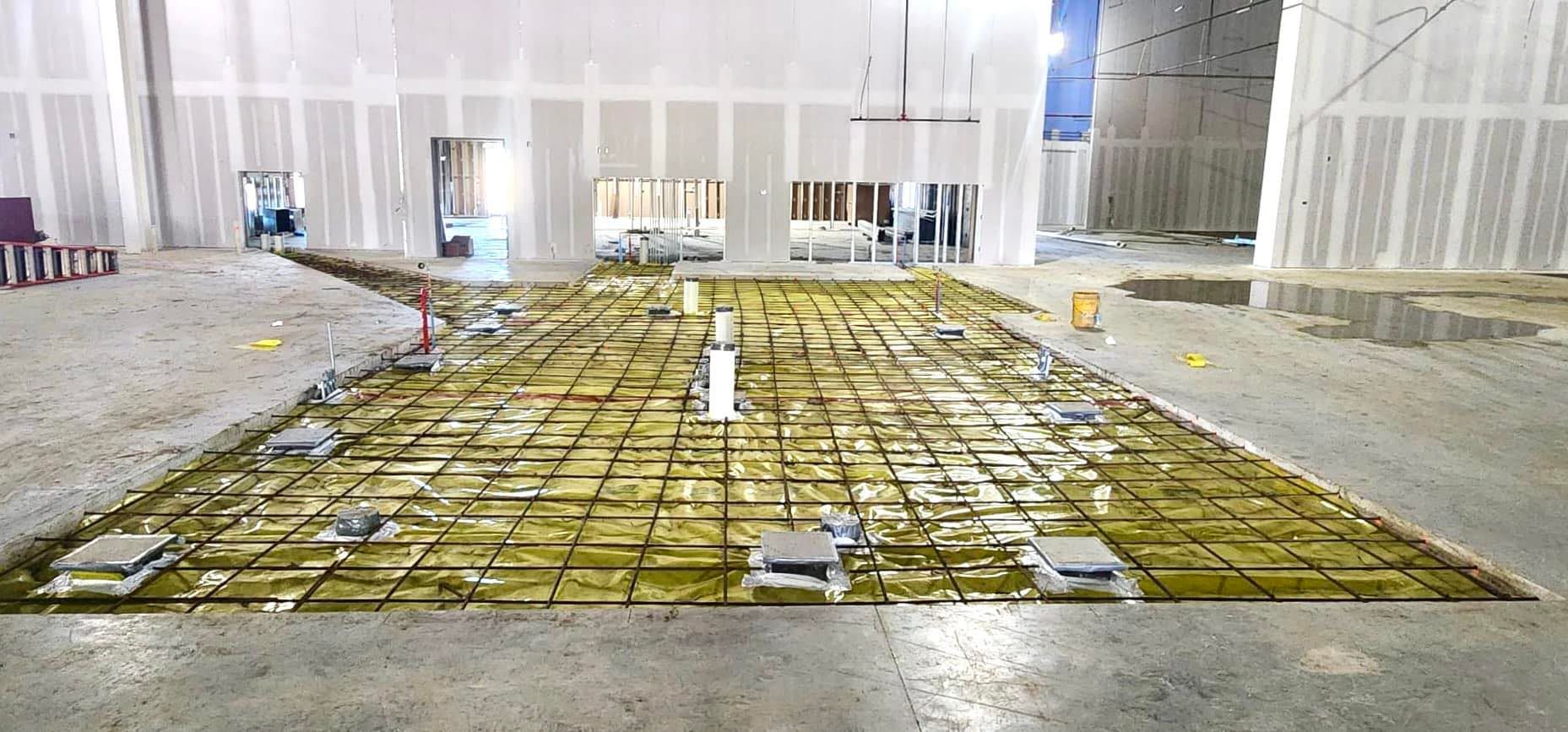 A concrete floor is being poured in a building under construction.