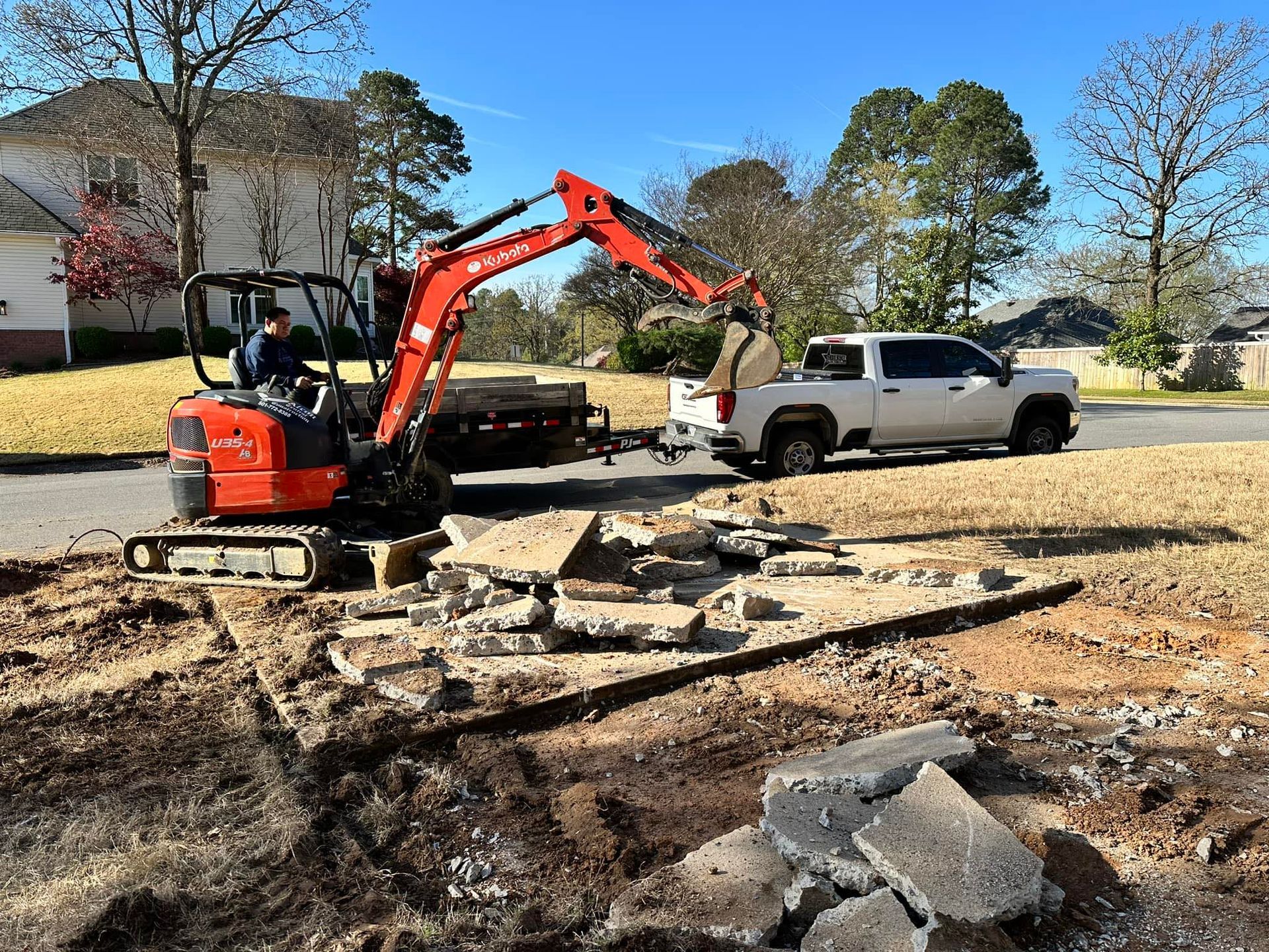 A truck is being towed by a small excavator.