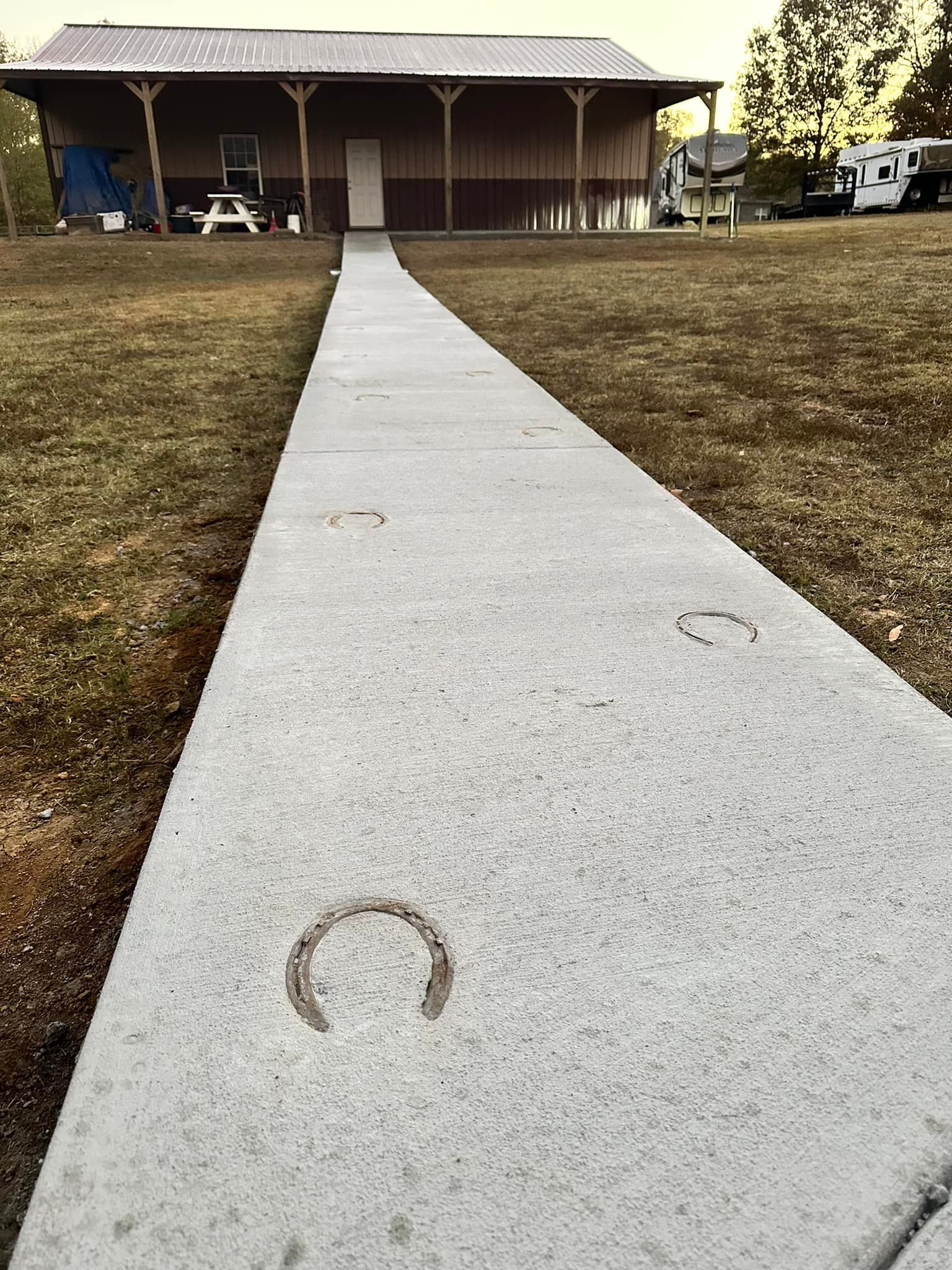 A concrete walkway leading to a building with horseshoe prints on it.