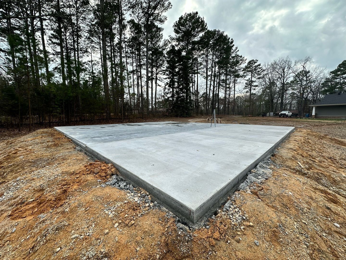 A concrete slab is sitting in the middle of a dirt field with trees in the background.