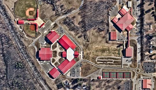 A sunset over a lake with trees in the foreground and a bridge in the background.