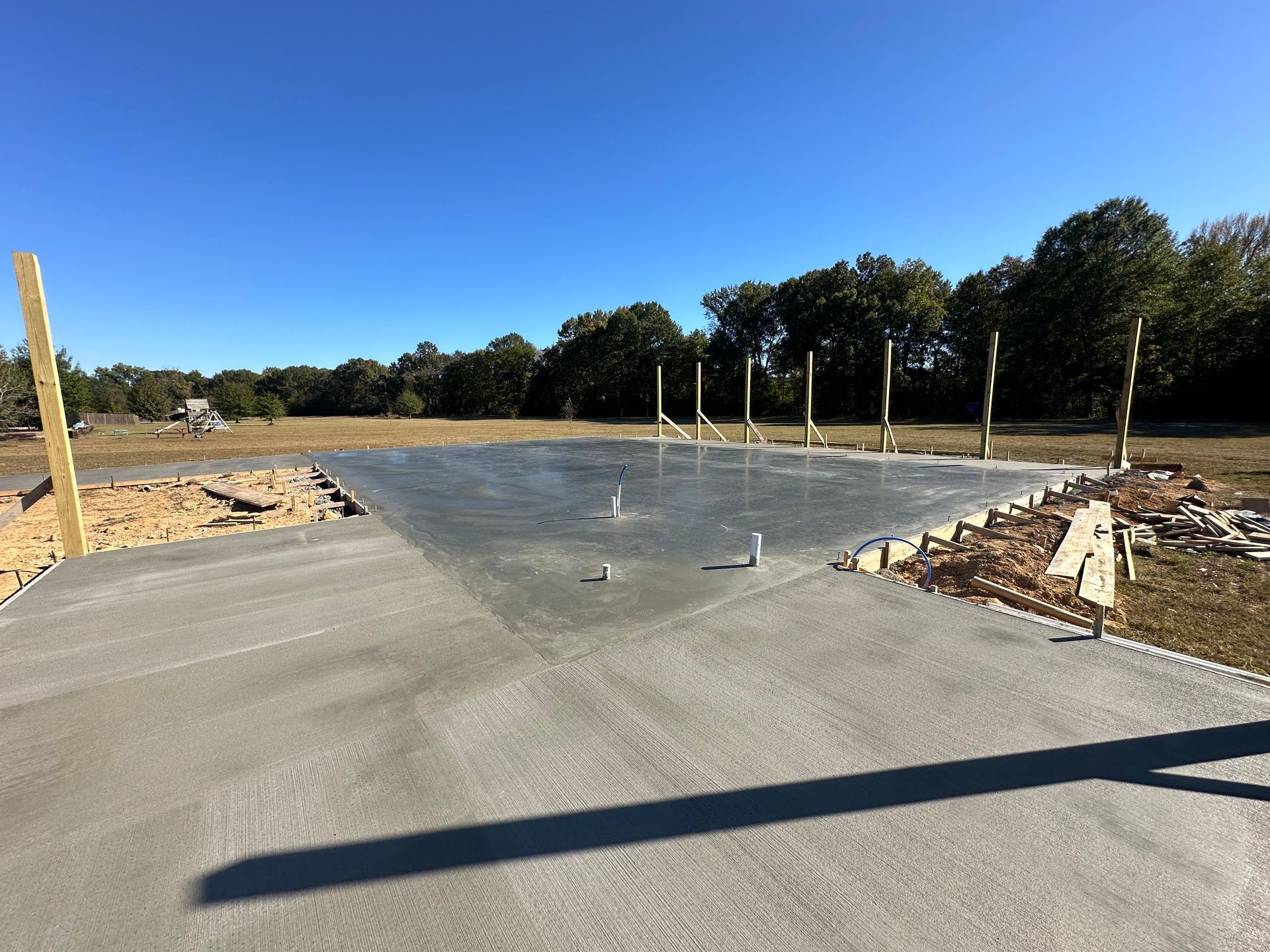 A concrete floor is being built in a field with trees in the background.