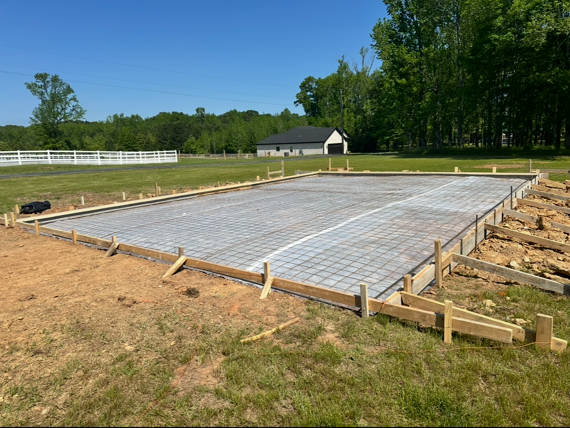 A concrete foundation is being built in a grassy field.