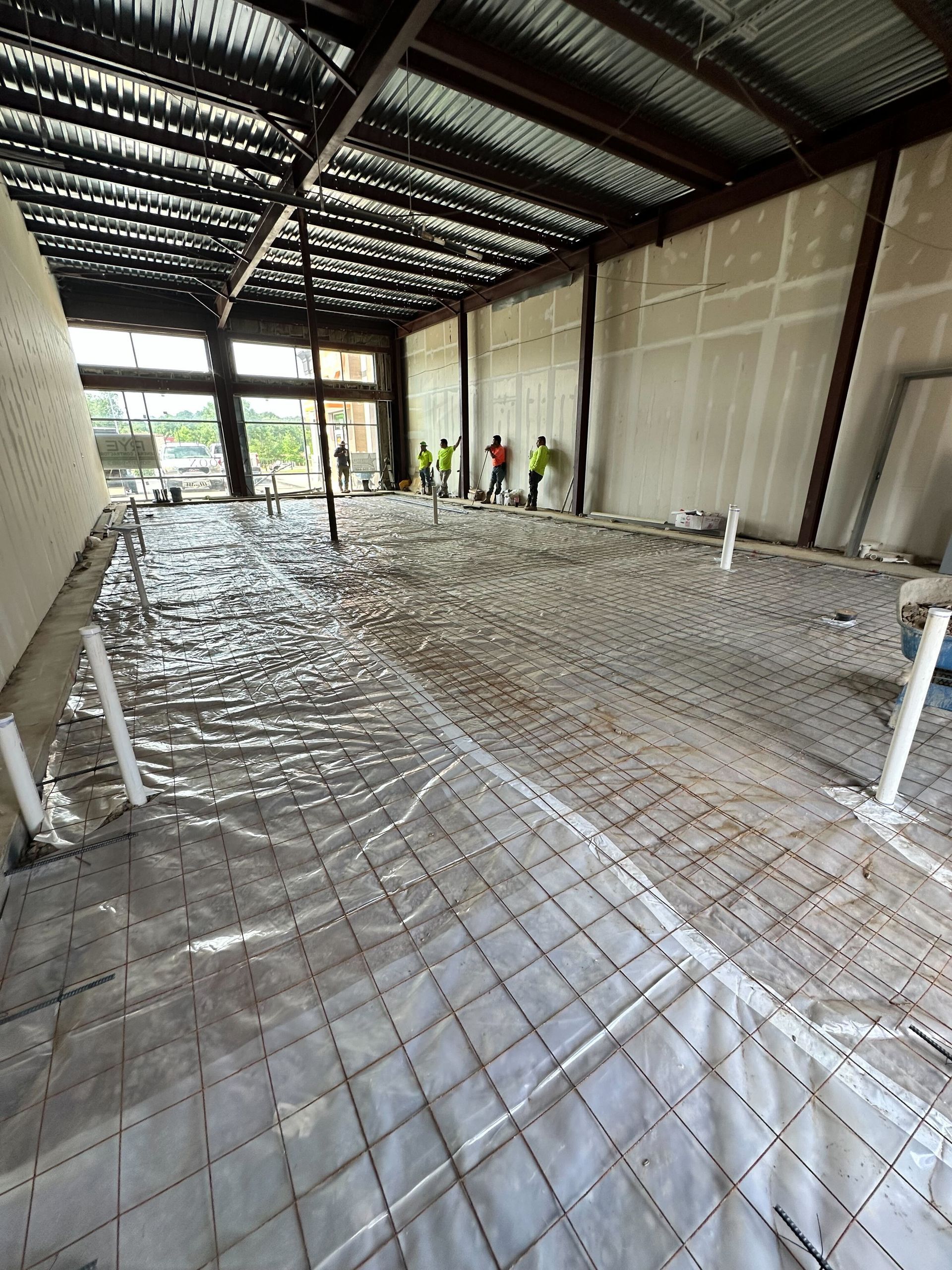 A group of construction workers are working on the floor of a building under construction.