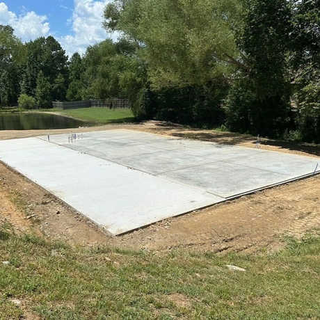 A large concrete slab is sitting in the middle of a dirt field with trees in the background.