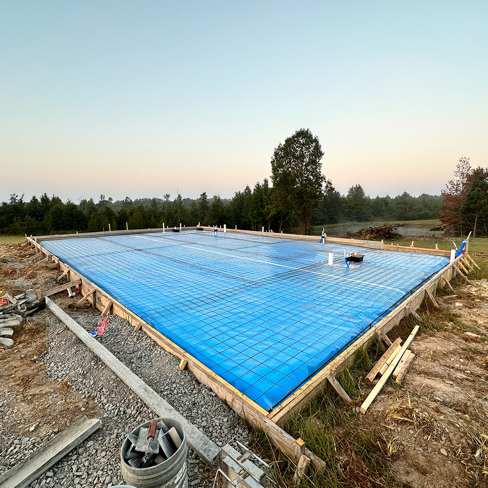 A concrete driveway leading to a house with trees in the background