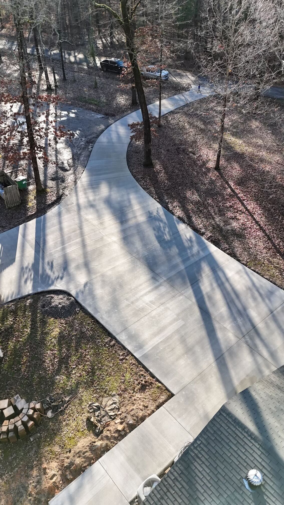 An aerial view of a concrete driveway surrounded by trees.