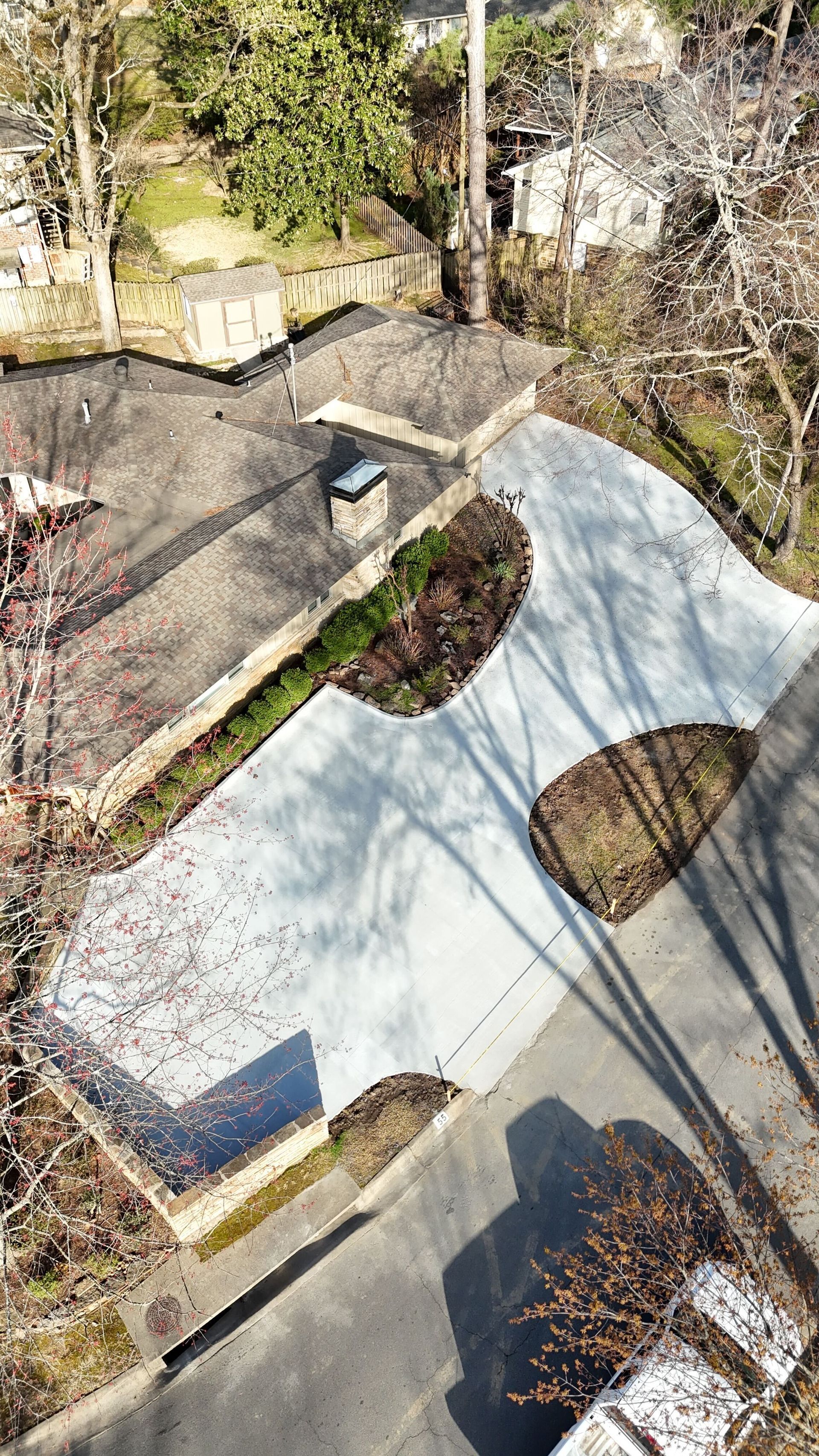 A concrete driveway leading to a house with trees in the background.