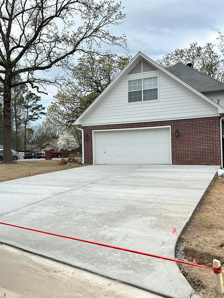A brick house with a concrete driveway in front of it.