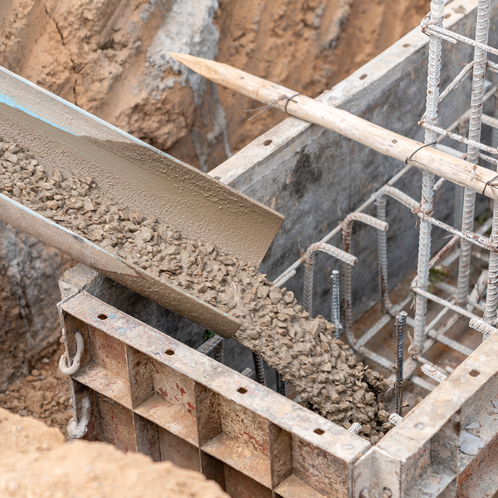 A concrete driveway leading to a house with trees in the background