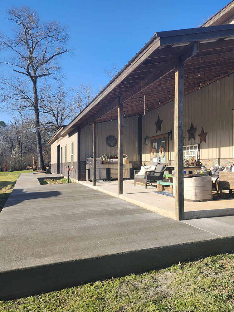 A house with a covered porch and a concrete walkway leading to it.