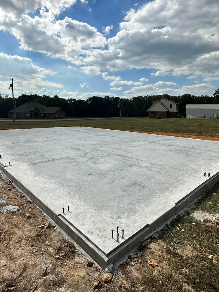 A concrete base for a house is being built in a field.