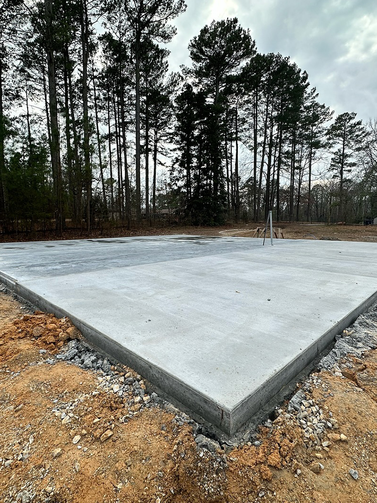 A large concrete slab is sitting in the middle of a dirt field with trees in the background.