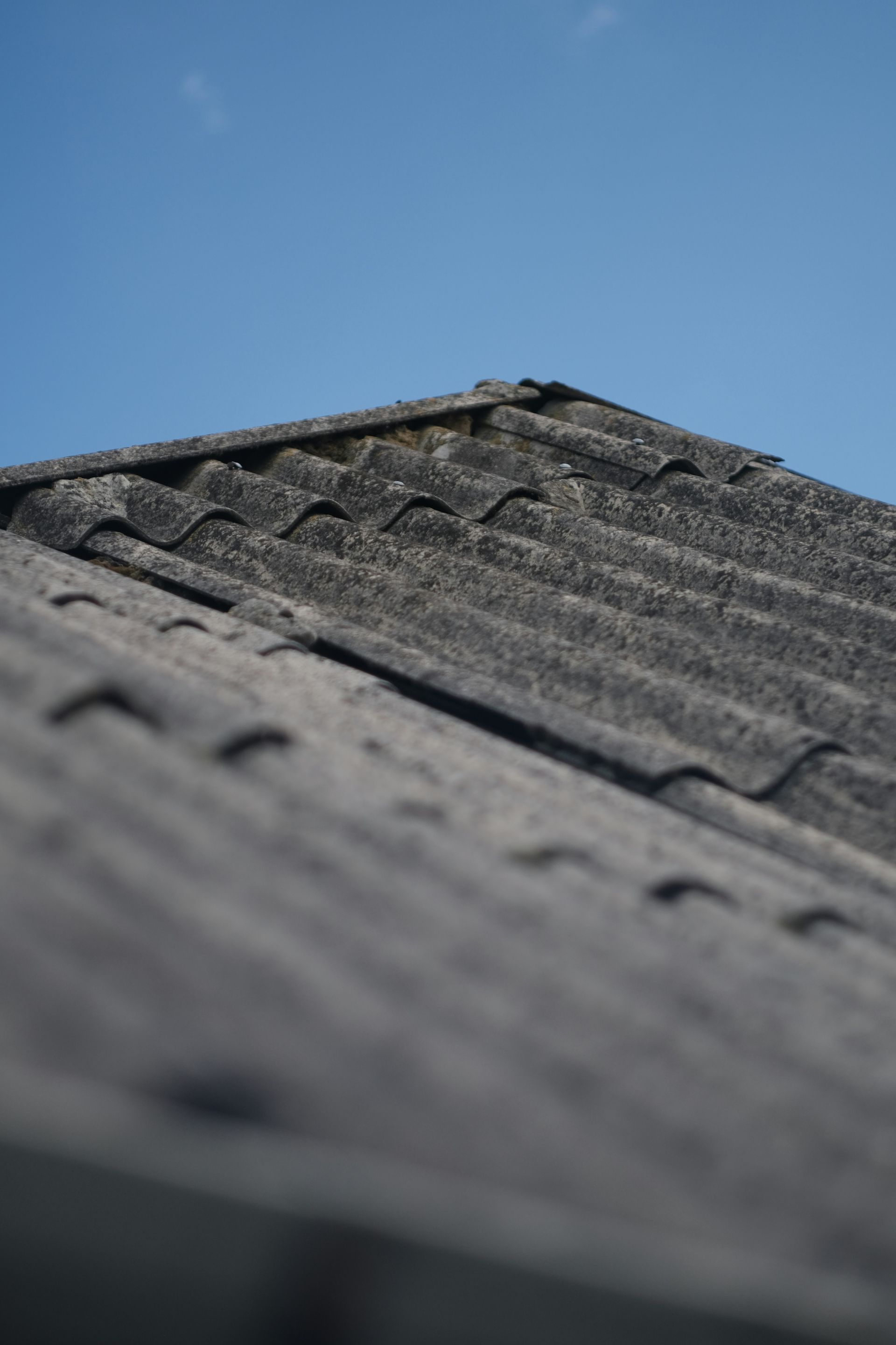 Weathered dark tiled roof with visible wear, uneven surface needs metal roof replacement 