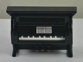 A small black piano is sitting on top of a white table.