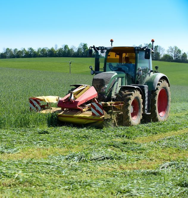 A Tractor Is Cutting Grass In A Field — Cane Country Slashing & Mowing In Marian, QLD