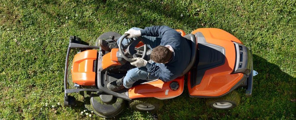 A Man Is Riding A Lawn Mower Through A Lush Green Field — Cane Country Slashing & Mowing In Marian, QLD