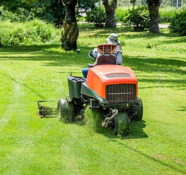 A Man Is Riding A Lawn Mower On A Lush Green Lawn — Cane Country Slashing & Mowing In Marian, QLD