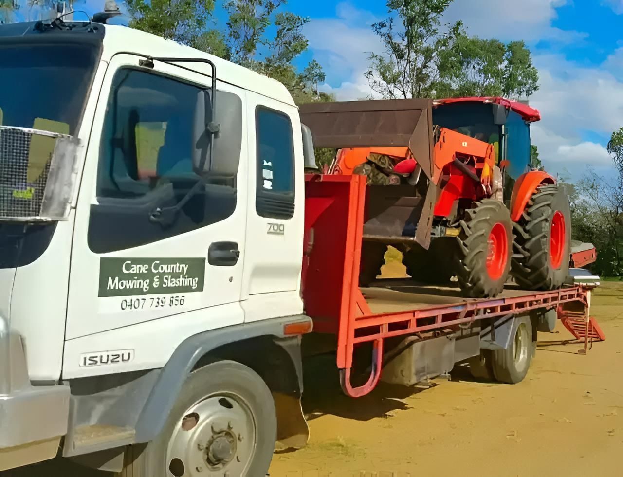 A White Truck With A Tractor On The Back Of It — Cane Country Slashing & Mowing In Marian, QLD