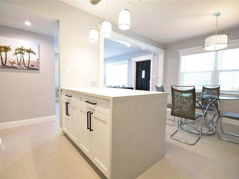 A kitchen with a large island and a dining room table and chairs.