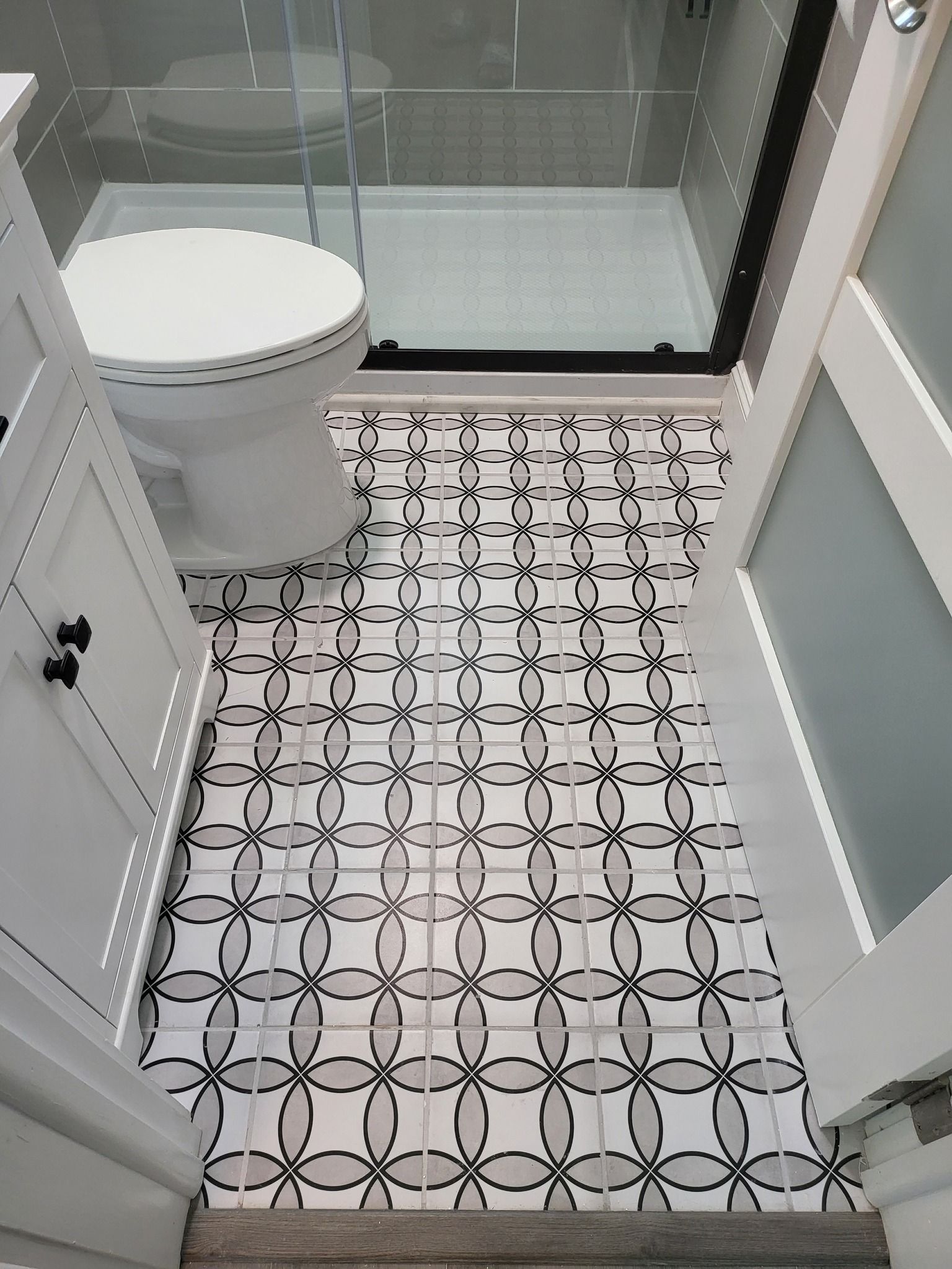 A bathroom with a toilet and a shower with a black and white tile floor.