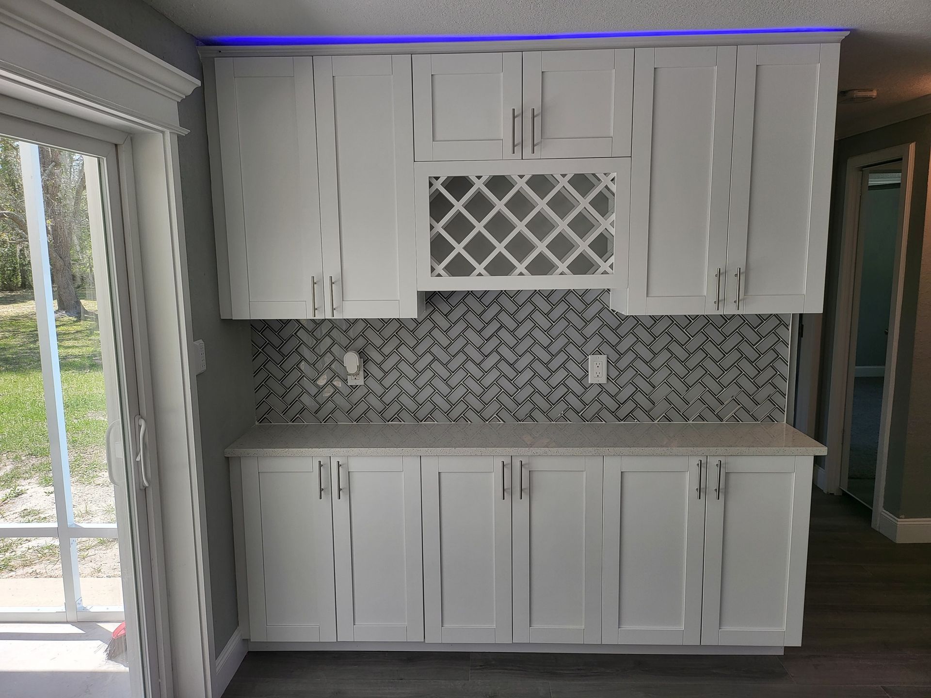 A kitchen with white cabinets and a wine rack on the wall.