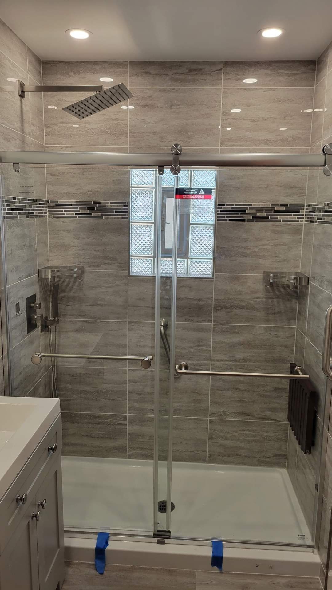 A bathroom with a sliding glass shower door and a tub.