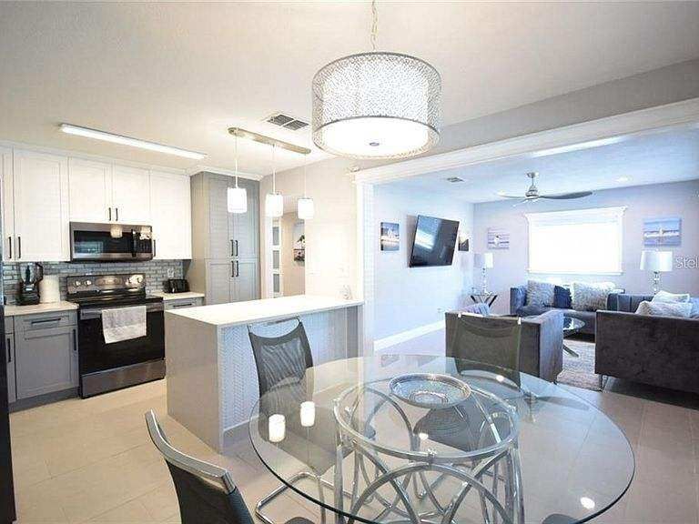 A kitchen and dining room in a house with a glass table and chairs.
