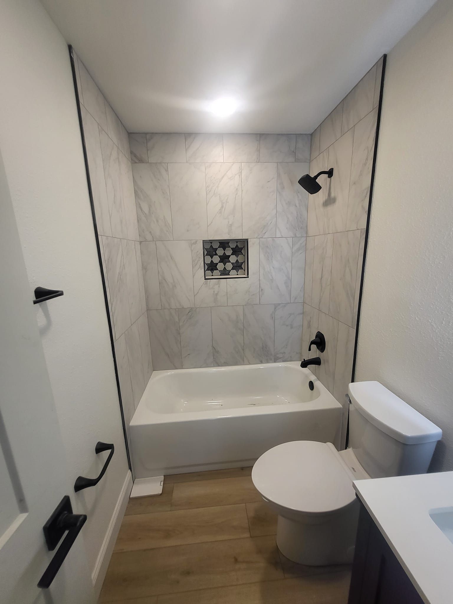 A bathroom with a tub , toilet , sink and shower.