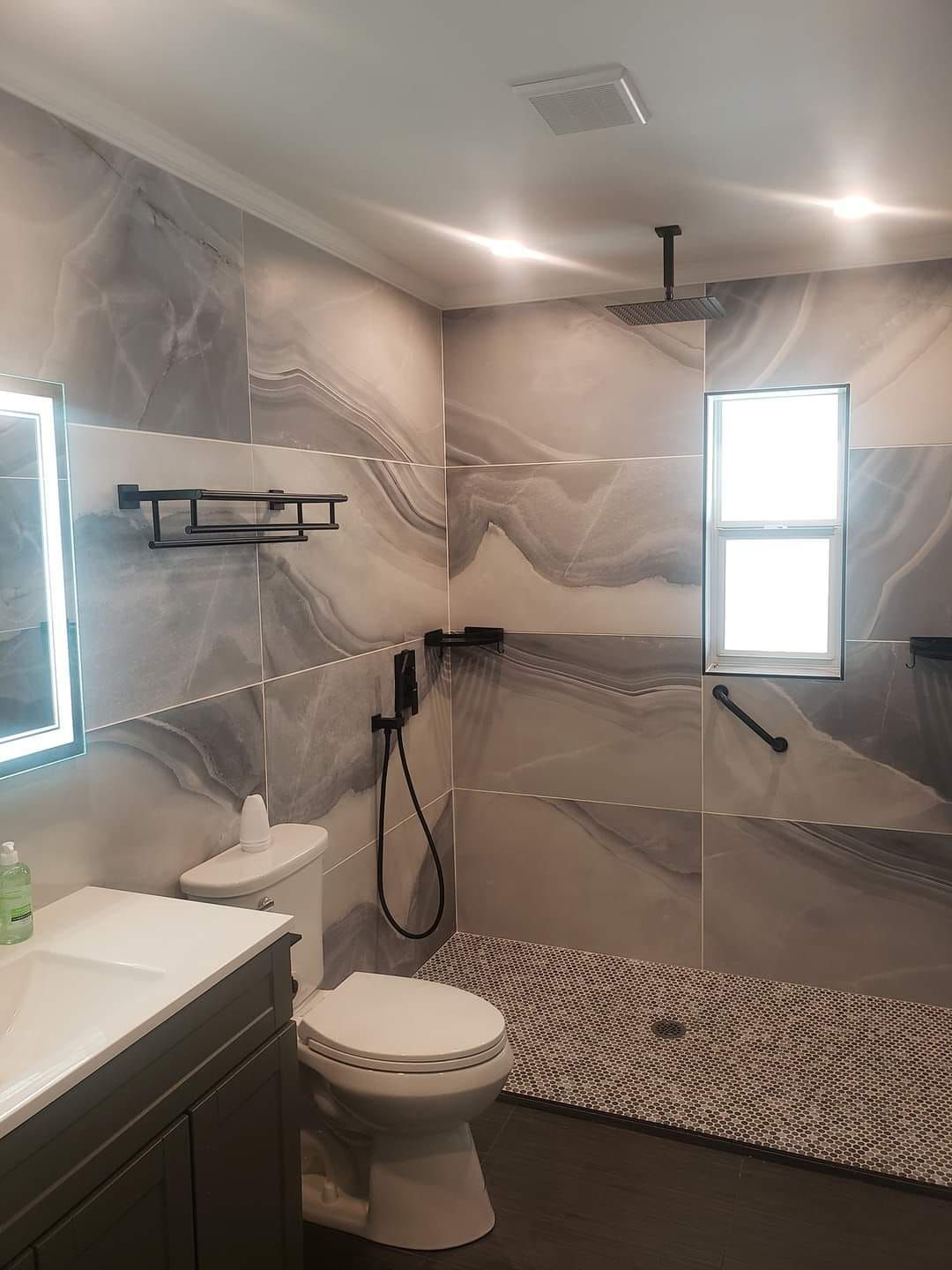 A bathroom with a toilet , sink and walk in shower.